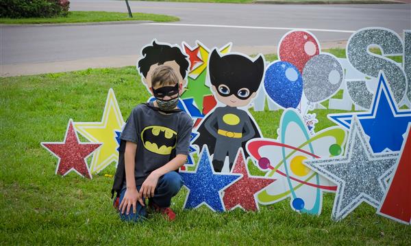 People pose next to superhero sign